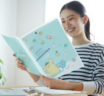 笑顔でポムポムプリンの冊子を見ている女性