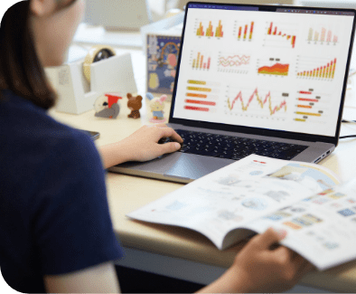 ノートパソコンに表示されたカラフルなグラフを見ながら資料を確認している
